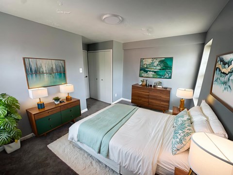 A bedroom with a bed, nightstands, and a painting on the wall.